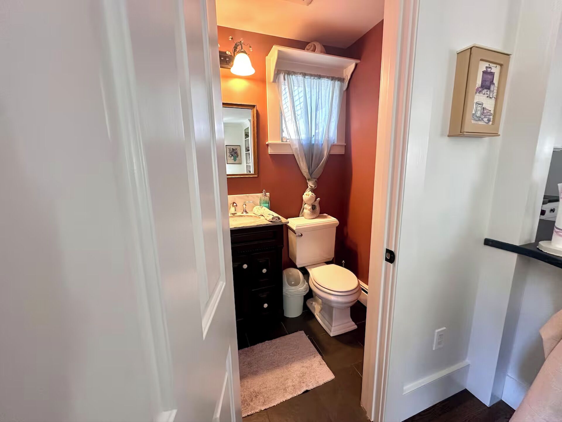 A bathroom with a toilet, sink, and a small window with curtains.