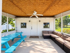 Un patio techado con un ventilador de techo, una mesa de picnic y un área de descanso.