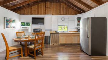 A kitchen with wooden cabinets, a stainless steel refrigerator, a microwave, and a dining table with chairs.
