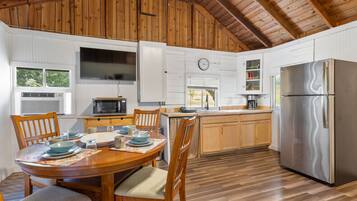 A kitchen with wooden cabinets, a stainless steel refrigerator, a microwave, and a dining table with chairs.