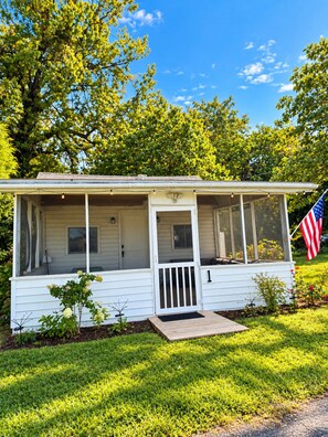 A single-story house with a porch, a small front yard, and an American flag.