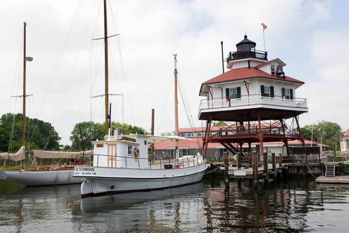 A white boat docked at a marina with a red-roofed building nearby.