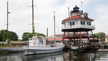 A white boat docked at a marina with a red-roofed building nearby.