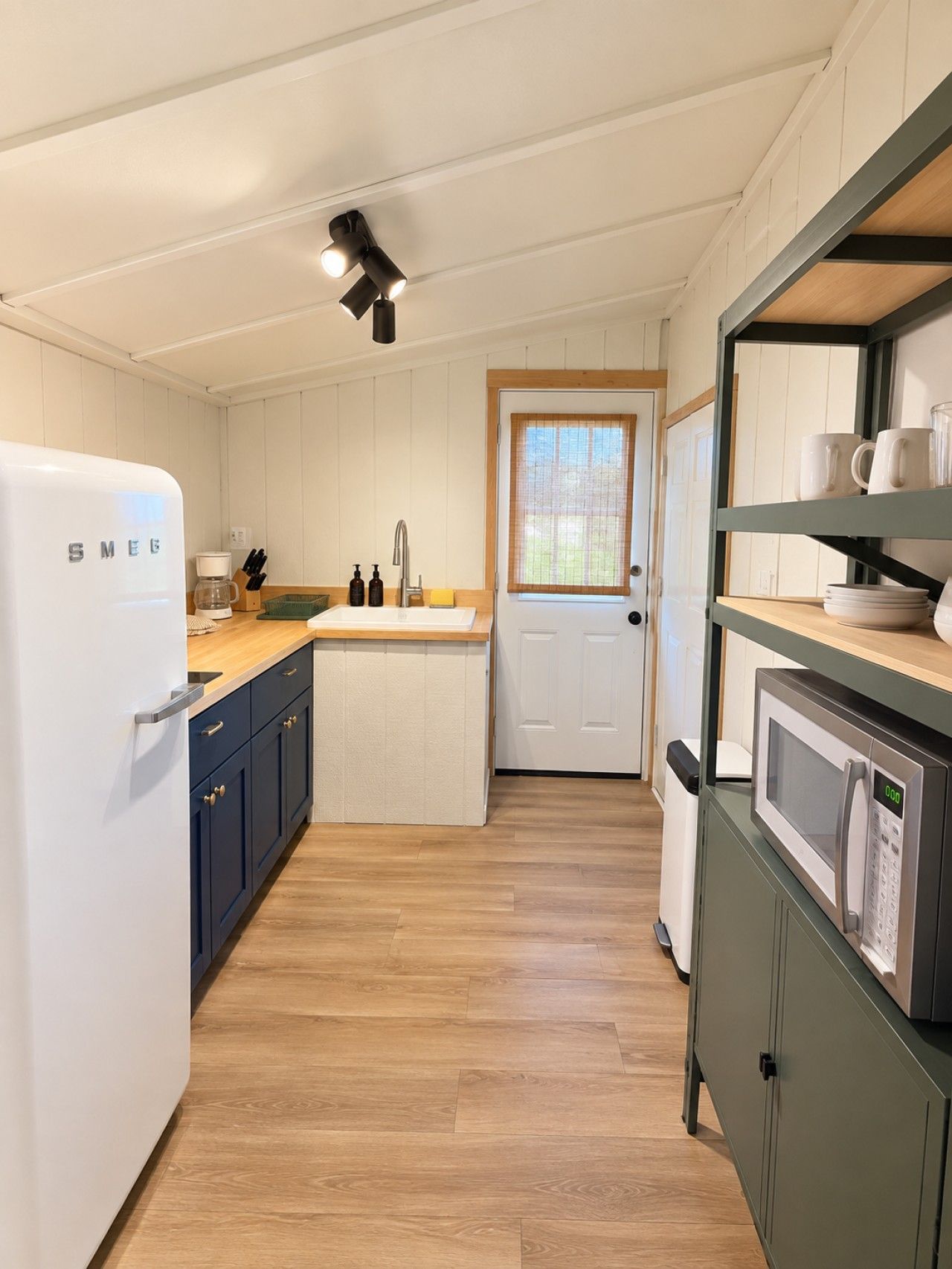 Una cucina compatta con un frigorifero bianco, un lavello e un forno a microonde.