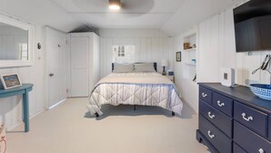 A bedroom with a bed, a dresser, a mirror, and a window.