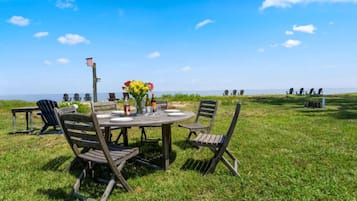 An outdoor dining area with a wooden table and chairs, a bottle of wine, and a vase of flowers.