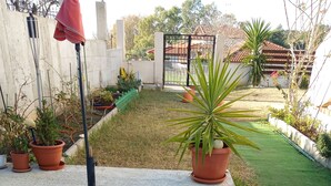 Un pastel con el número '2025' escrito, sobre una mesa azul al aire libre, con plantas en macetas y un jardín de fondo.