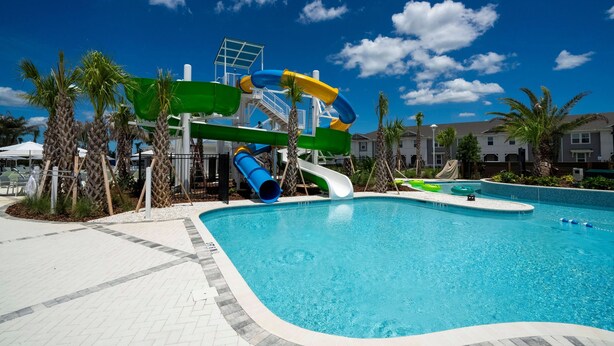A swimming pool with a water slide and a lifeguard tower. - Windsor Cay 7BR Water Park Free (Clermont)