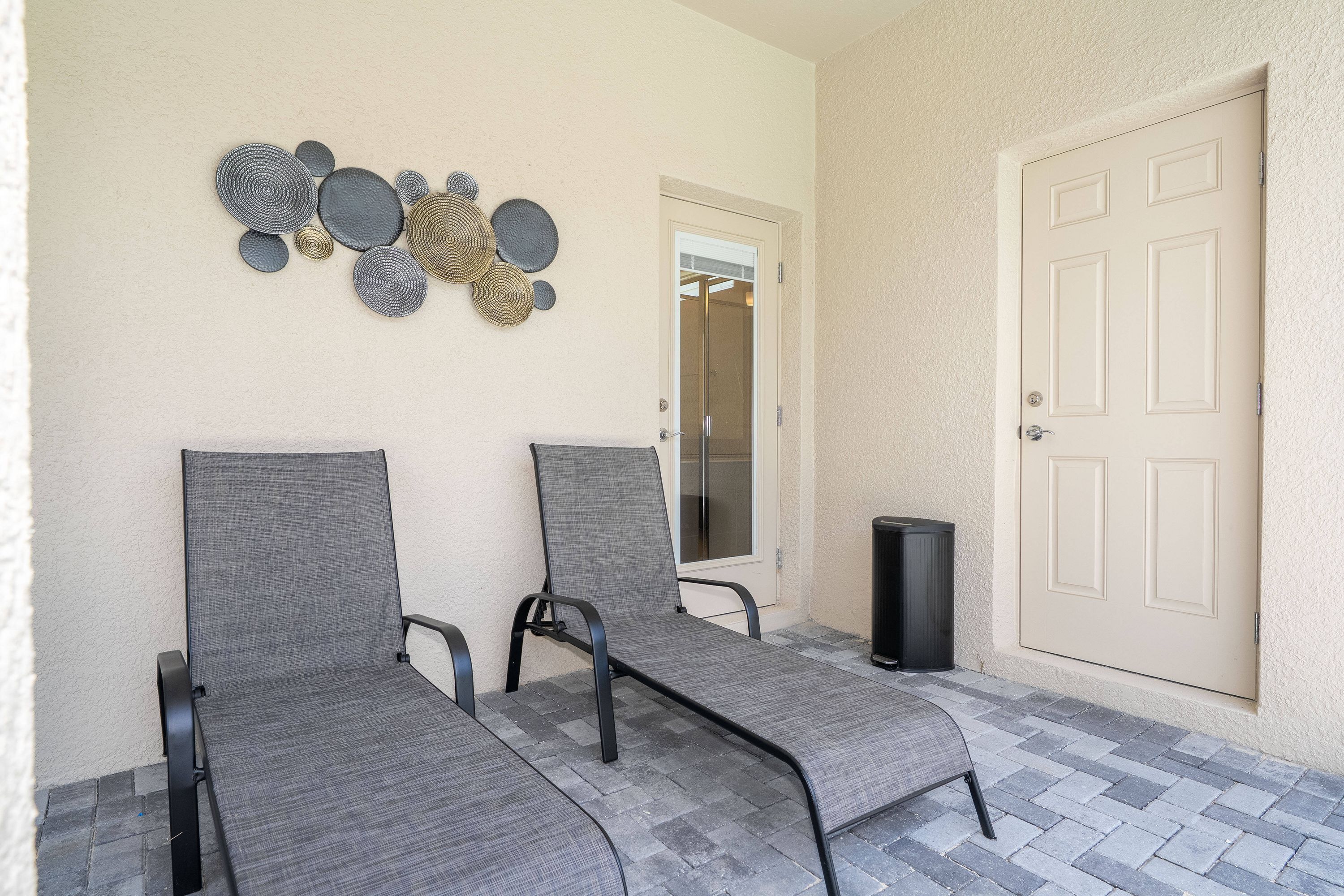 Two grey lounge chairs with metal frames, a beige door, and a wall-mounted decorative piece.