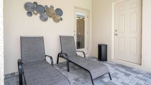 Two grey lounge chairs with metal frames, a beige door, and a wall-mounted decorative piece. - Windsor Cay 7BR Water Park Free (Clermont)