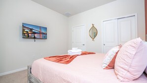 A bedroom with a bed, a painting of a bridge, a mirror, and two doors. - Windsor Cay 7BR Water Park Free (Clermont)