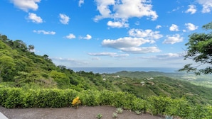 A lush green landscape with a clear sky and scattered clouds. - Mountainside Home with Modern Design, Sweeping Ocean Views & Private Swimming Pool (Tempate)