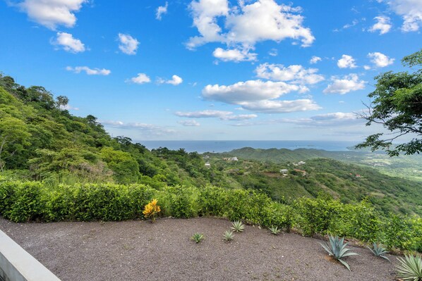 A lush green landscape with a clear sky and scattered clouds. - Mountainside Home with Modern Design, Sweeping Ocean Views & Private Swimming Pool (Tempate)
