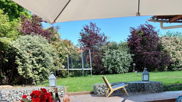 Patio esterno con tavolo apparecchiato per la cena, circondato da muri in pietra e vegetazione.