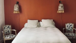 Una camera da letto con un letto grande, due lampade a parete e due poltrone a fantasia.