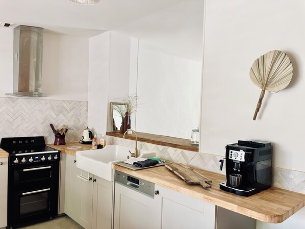 Una cocina moderna con horno integrado, cafetera y encimera de madera.