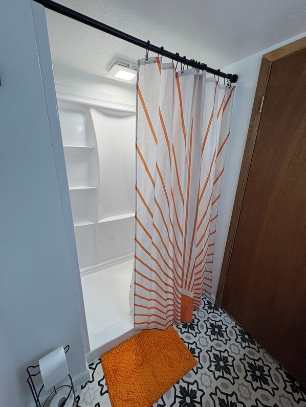 Un baño con cortina de ducha, una toalla y suelo estampado.