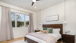 A bedroom with a large bed, bedside tables, a ceiling fan, and a window with curtains. - Trinity Beats-private Rooftop Deck-east Nashville (Nashville)