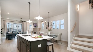 A modern kitchen with a central island, pendant lighting, and a dining area with a table and chairs. - Trinity Beats-private Rooftop Deck-east Nashville (Nashville)