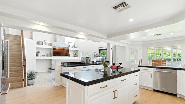 A spacious kitchen with white cabinetry, a black countertop, and a stainless steel dishwasher. - Splash Canyon - Splash Pad & Tons of Games - Gym (Chandler)