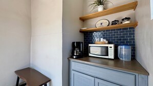 Una cocina compacta con microondas, cafetera y una pequeña mesa.