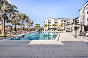 A swimming pool with lounge chairs and palm trees, surrounded by buildings with balconies. - Contemporary Stay 10 min to Parks Pets Friendly (Bay Lake)
