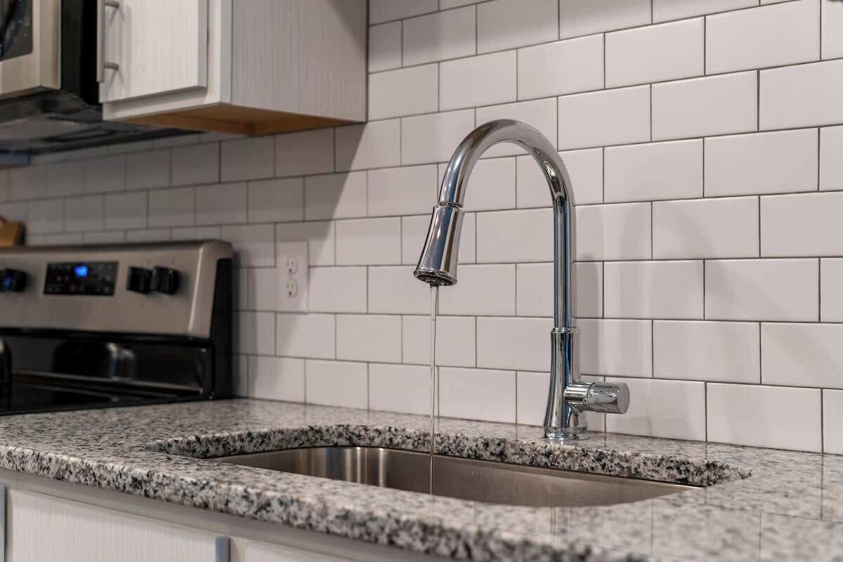 A kitchen with a stainless steel sink, a modern faucet, and a built-in oven.