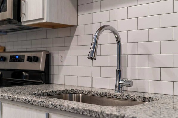 A kitchen with a stainless steel sink, a modern faucet, and a built-in oven.