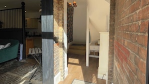 A spacious living area with a brick fireplace, a green sofa, and a staircase leading to another level.