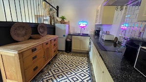 A modern kitchen with a neon sign, wooden cabinets, and a patterned rug.