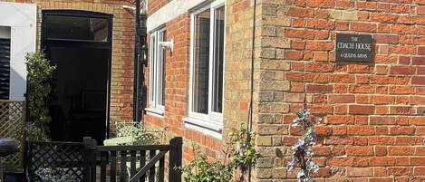 Ein Backsteinhaus mit einem Schild, auf dem 'The Coach House 6 Queens Mews' steht.