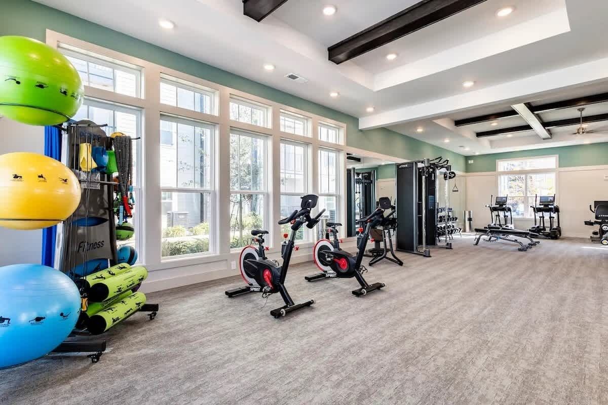 A spacious gym with cardio equipment, weight machines, and exercise balls.