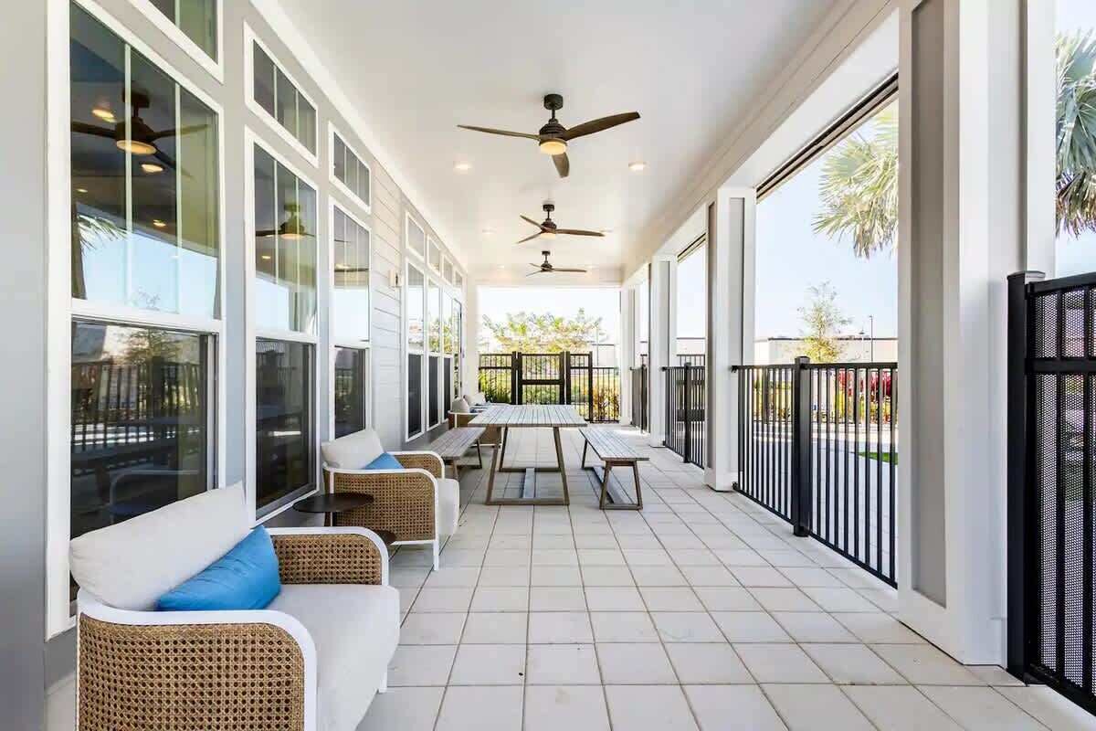 Un espace extérieur abrité, aménagé avec des meubles en osier, une table centrale et des ventilateurs de plafond.
