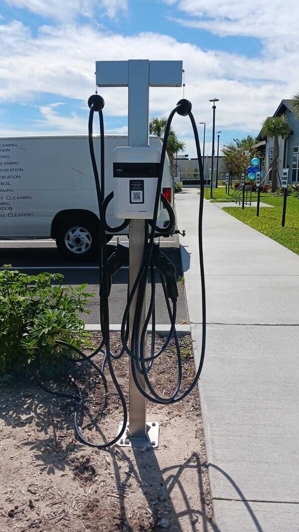 A portable power station with multiple cables connected to it, placed on a sidewalk next to a road.