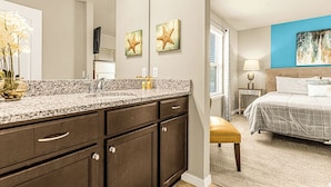 Un baño moderno con encimera de granito, muebles oscuros y un espejo grande.