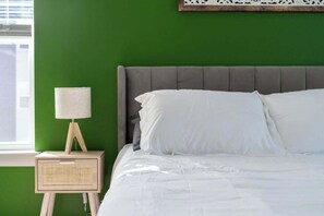 A bed with white bedding, a grey headboard, and a bedside table with a lamp and a radio. - Cozy 2Bed Boho Hideaway 10 Min to Parks Allows Pet (Bay Lake)