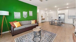 Ein modernes Wohnzimmer mit grüner Akzentwand, einer Couch, einem Couchtisch und einem Deckenventilator.