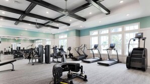 Ein Fitnessstudio mit verschiedenen Trainingsgeräten, darunter Laufbänder, Crosstrainer und Kraftstationen.