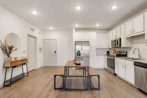 A modern kitchen with white cabinets, a stainless steel refrigerator, a microwave, and a dishwasher.