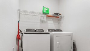 A laundry area with two washing machines, a drying rack, and a green bottle on a shelf. - Cozy 2Bed Boho Hideaway 10 Min to Parks Allows Pet (Bay Lake)