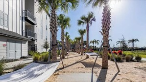 A pathway lined with palm trees leading to a building with a white facade and balconies. - Cozy 2Bed Boho Hideaway 10 Min to Parks Allows Pet (Bay Lake)