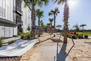A pathway lined with palm trees leading to a building with a white facade and balconies.