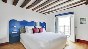 Ein Schlafzimmer mit blauem Kopfteil, weißer Bettwäsche und Holzboden.