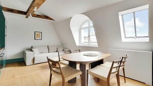Eine moderne Loftswohnung mit Essbereich, einer Couch und einem großen Fenster, das für natürliches Licht sorgt.