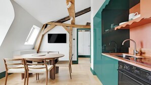Eine moderne Küche mit Geschirrspüler, Spüle und Arbeitsplatte. Ein Essbereich mit Tisch und Stühlen ist ebenfalls vorhanden.