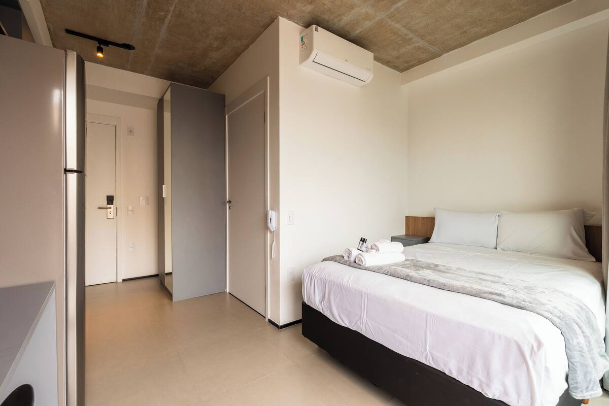 Een slaapkamer met een bed, een kledingkast en een deur naar een andere kamer.