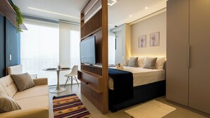 A modern hotel room with a bed, a TV, a desk, and a balcony.