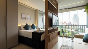 A modern hotel room with a bed, a TV, a balcony with a table and chairs, and a city view. - On Domingos de Morais (São Paulo)
