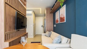 A modern living room with a TV, wooden paneling, a sofa, and artwork on the wall.