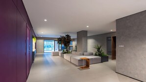 A modern reception area with a grey sofa, a wooden coffee table, and a large plant.